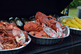 Lobster, corn, and baked potato on the grill and ready to serve